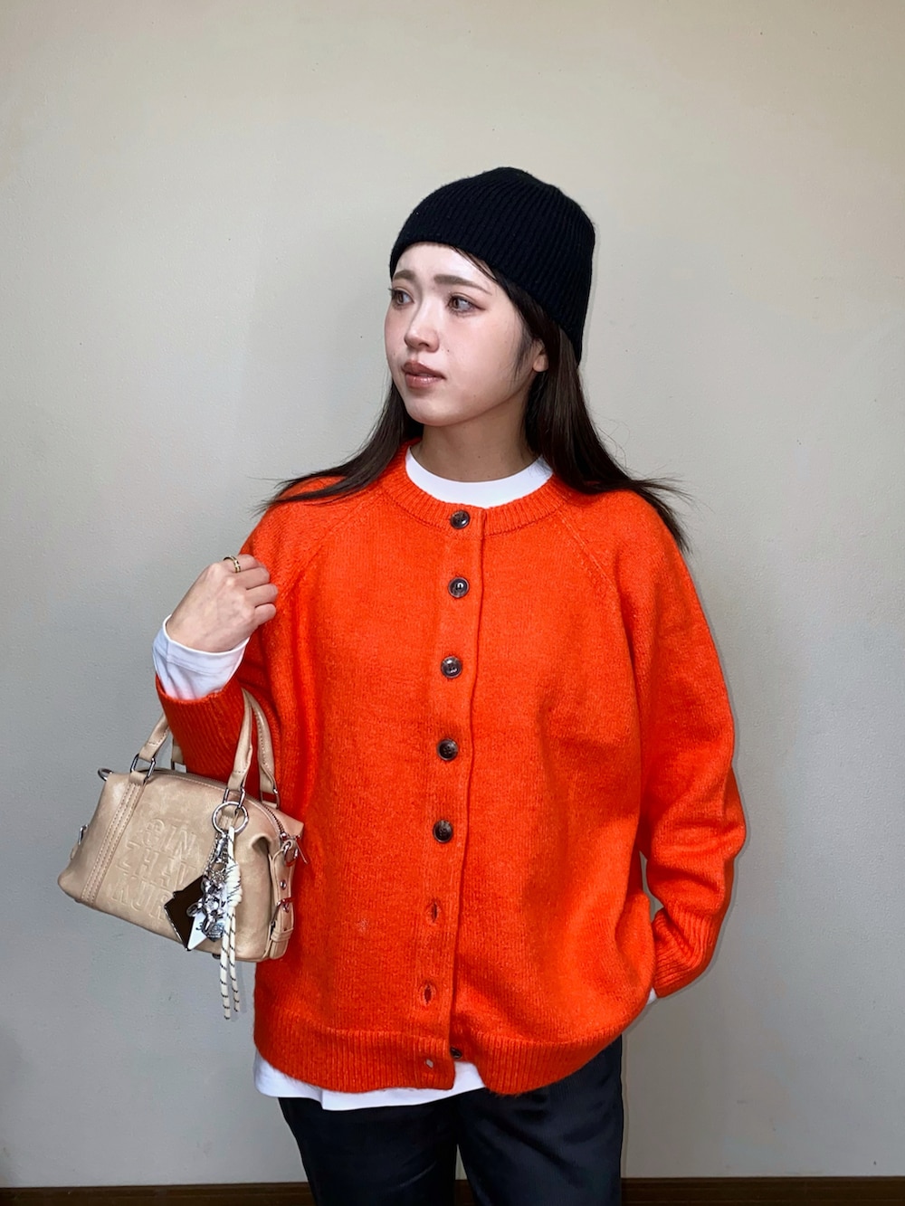 オレンジ系のニット/セーター、ブラック系のその他パンツ、ベージュ系のボストンバッグを着用したレディースの秋コーディネートの2枚目の写真