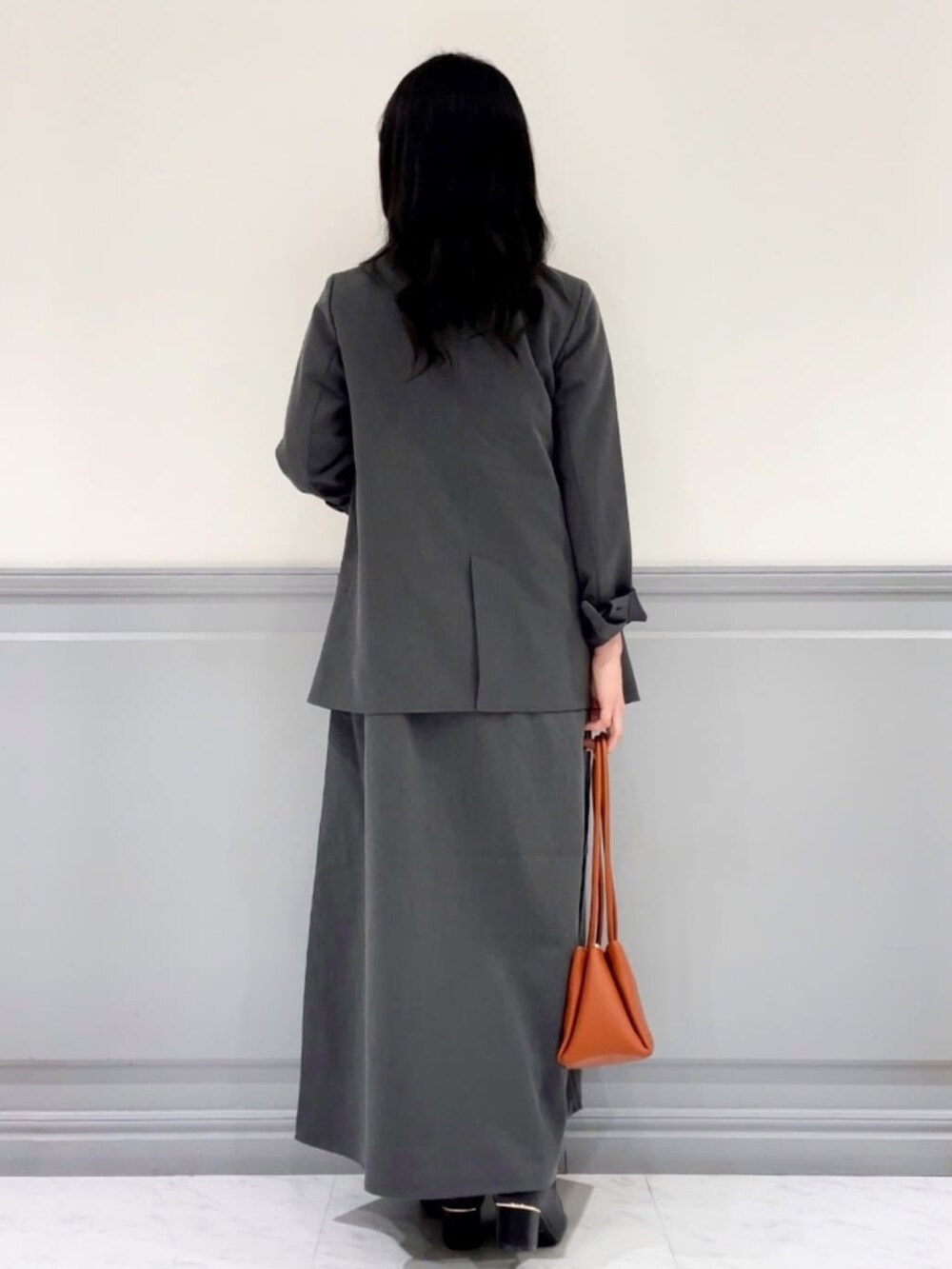 グレー系のテーラードジャケット、グレー系のワンピース、ホワイト系のTシャツ/カットソーを着用したレディースの秋コーディネートの3枚目の写真