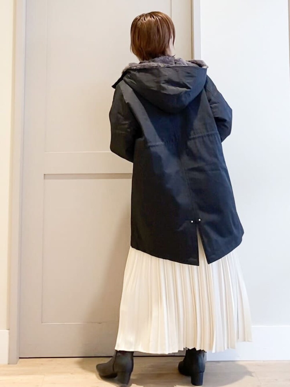 ブラック系のブルゾン、ベージュ系のニット/セーター、ホワイト系のスカートを着用したレディースの秋コーディネートの3枚目の写真