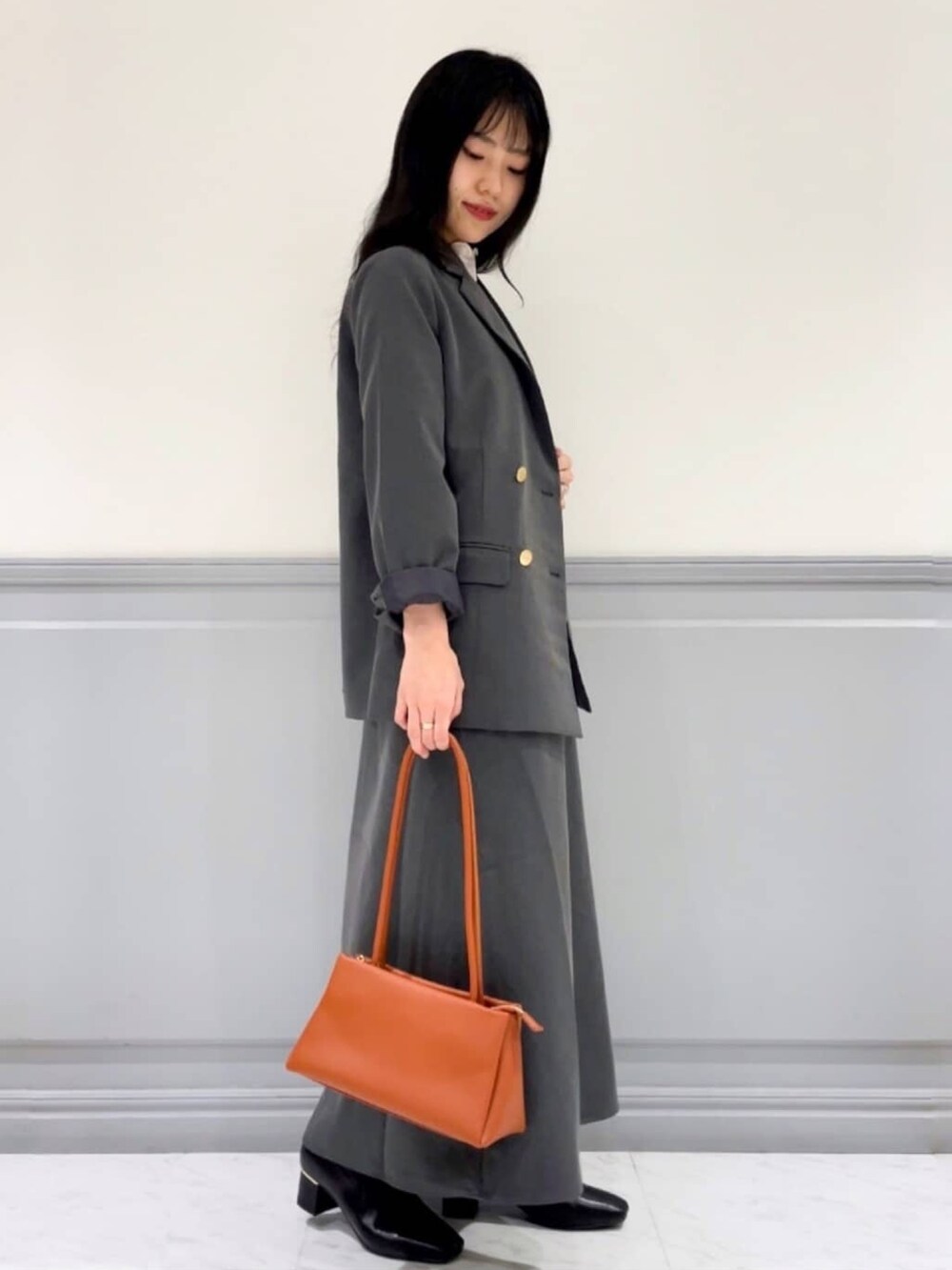 グレー系のテーラードジャケット、グレー系のワンピース、ホワイト系のTシャツ/カットソーを着用したレディースの秋コーディネートの2枚目の写真