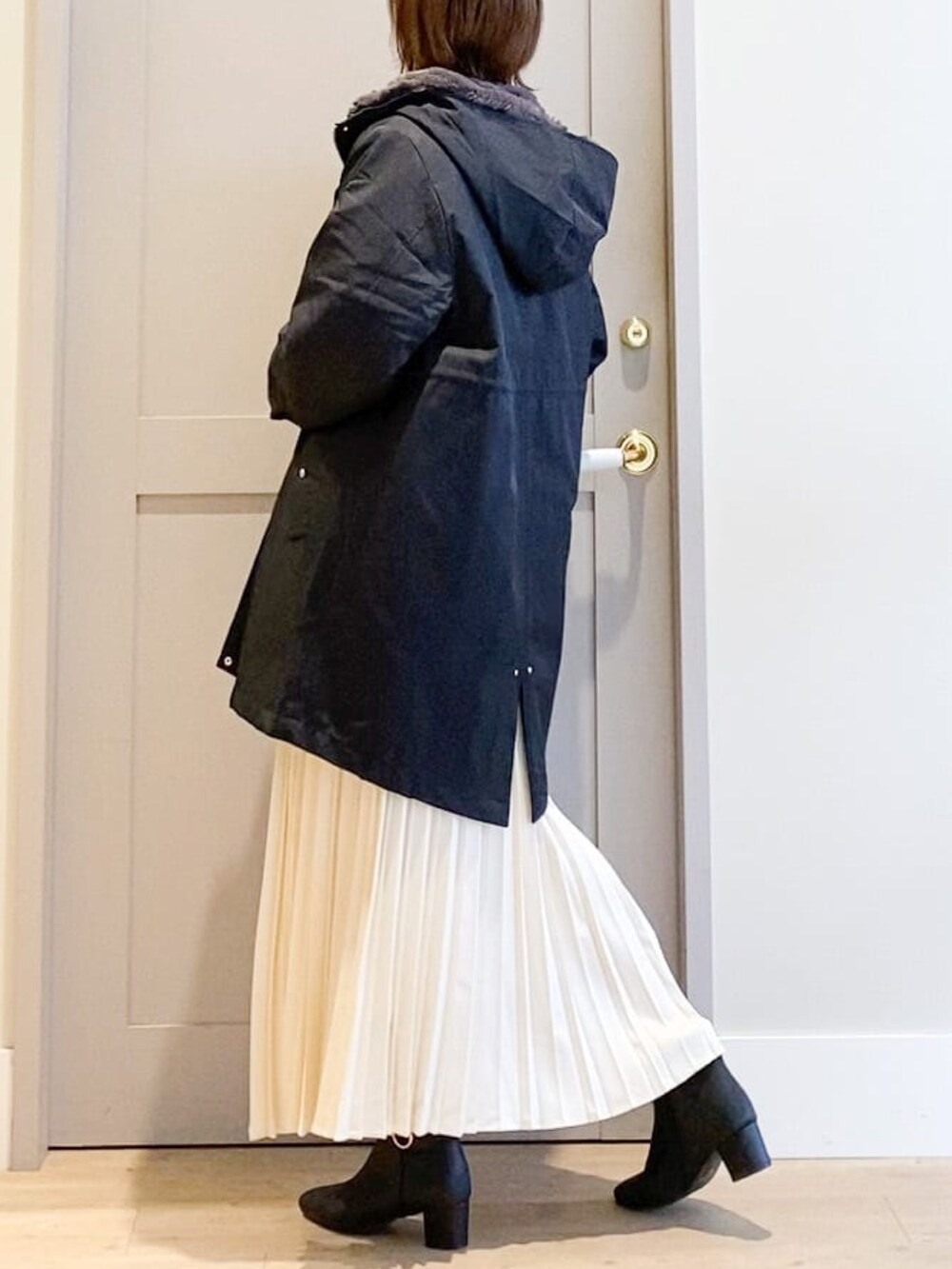 ブラック系のブルゾン、ベージュ系のニット/セーター、ホワイト系のスカートを着用したレディースの秋コーディネートの2枚目の写真