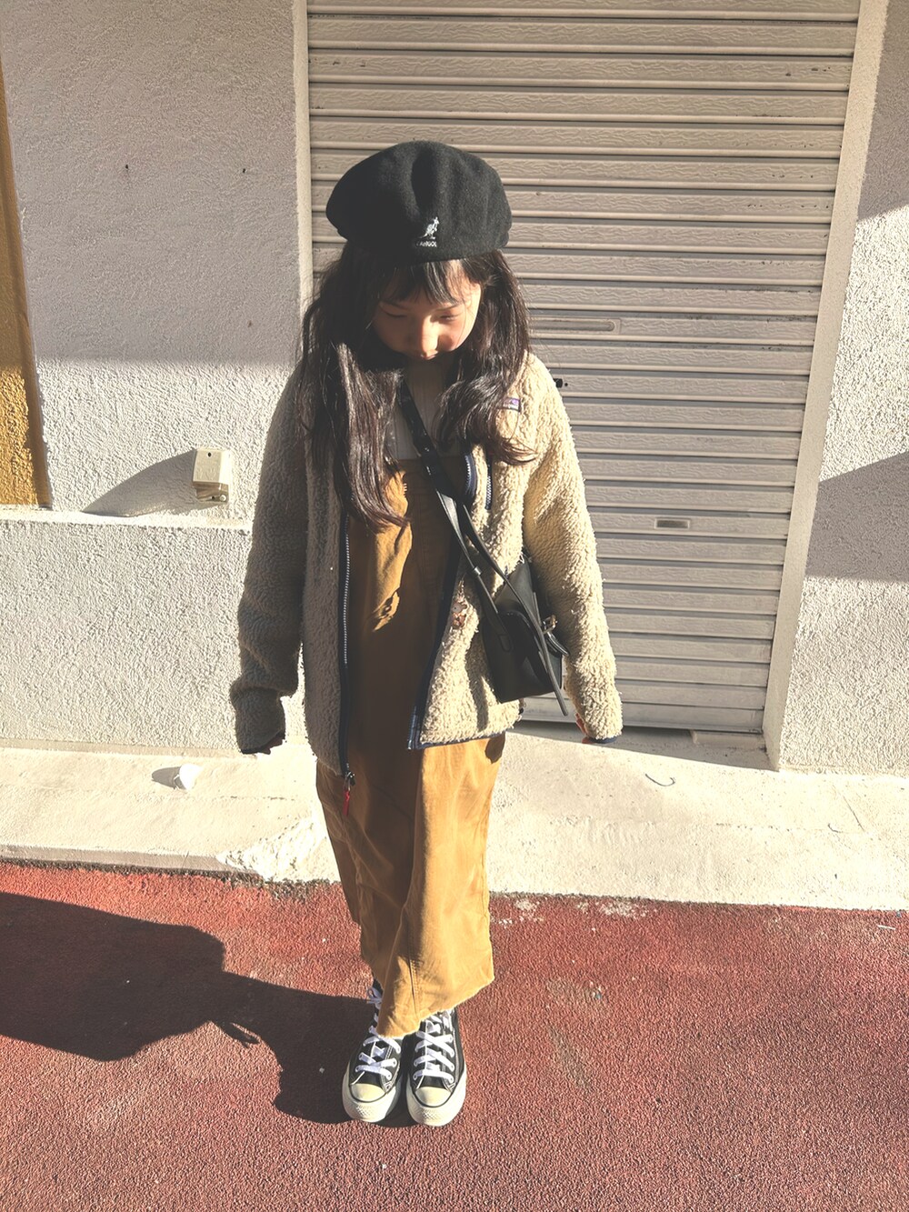 ベージュ系のノーカラーコート、ブラウン系のスカート、ブラック系のスニーカーを着用したキッズの春コーディネートの3枚目の写真