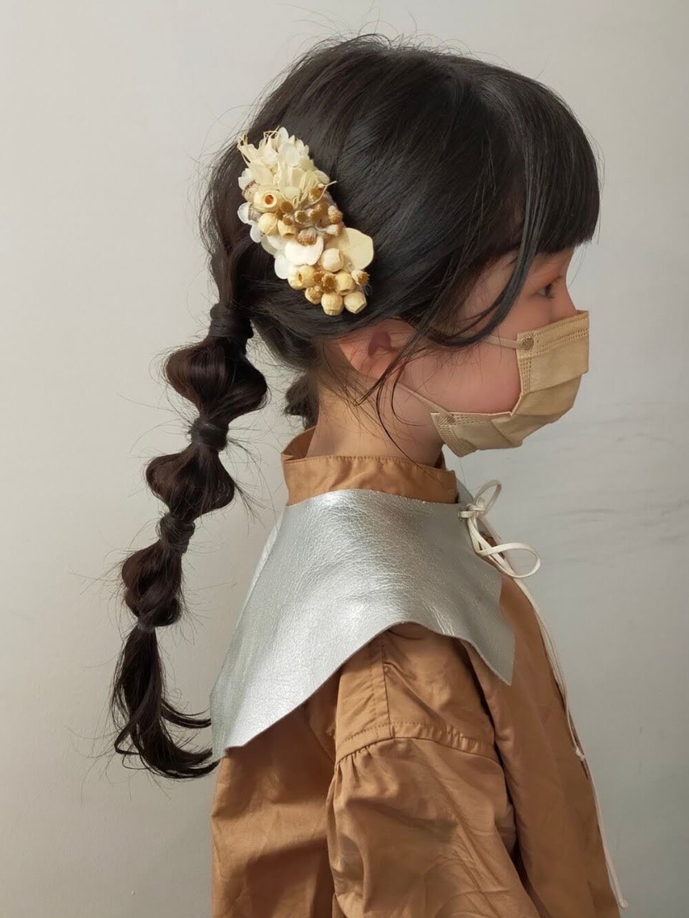 ベージュ系のシャツワンピース、ブラック系のスニーカー、ブラウン系のかごバッグを着用したキッズの春コーディネートの2枚目の写真