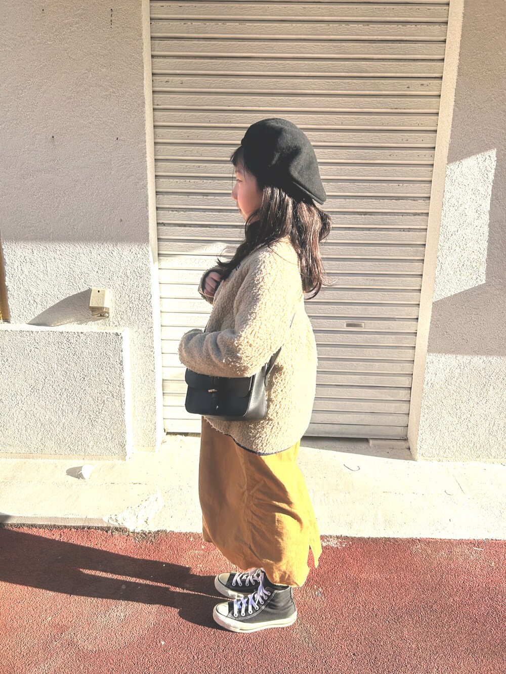 ベージュ系のノーカラーコート、ブラウン系のスカート、ブラック系のスニーカーを着用したキッズの春コーディネートの2枚目の写真