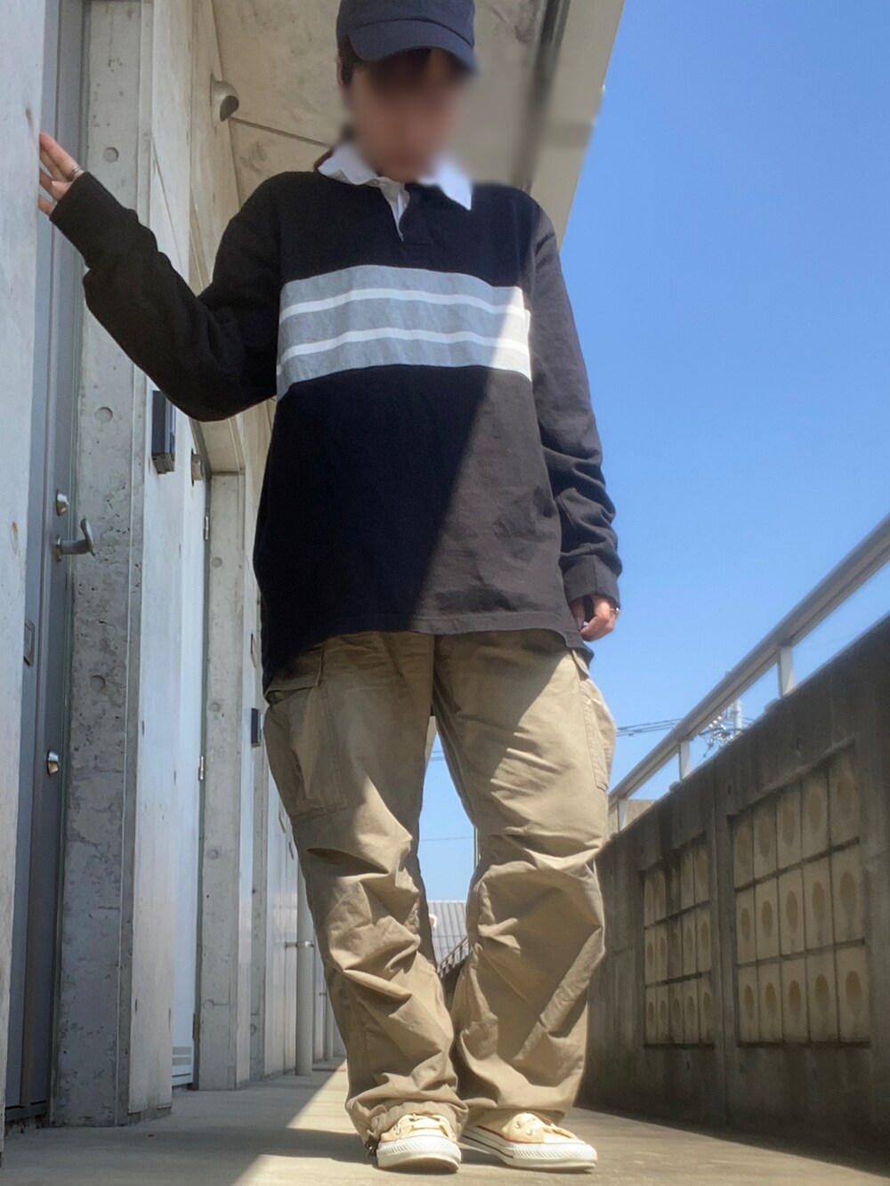 ブラック系のポロシャツ、ベージュ系のカーゴパンツ、ホワイト系のスニーカーを着用したレディースの春コーディネートの2枚目の写真
