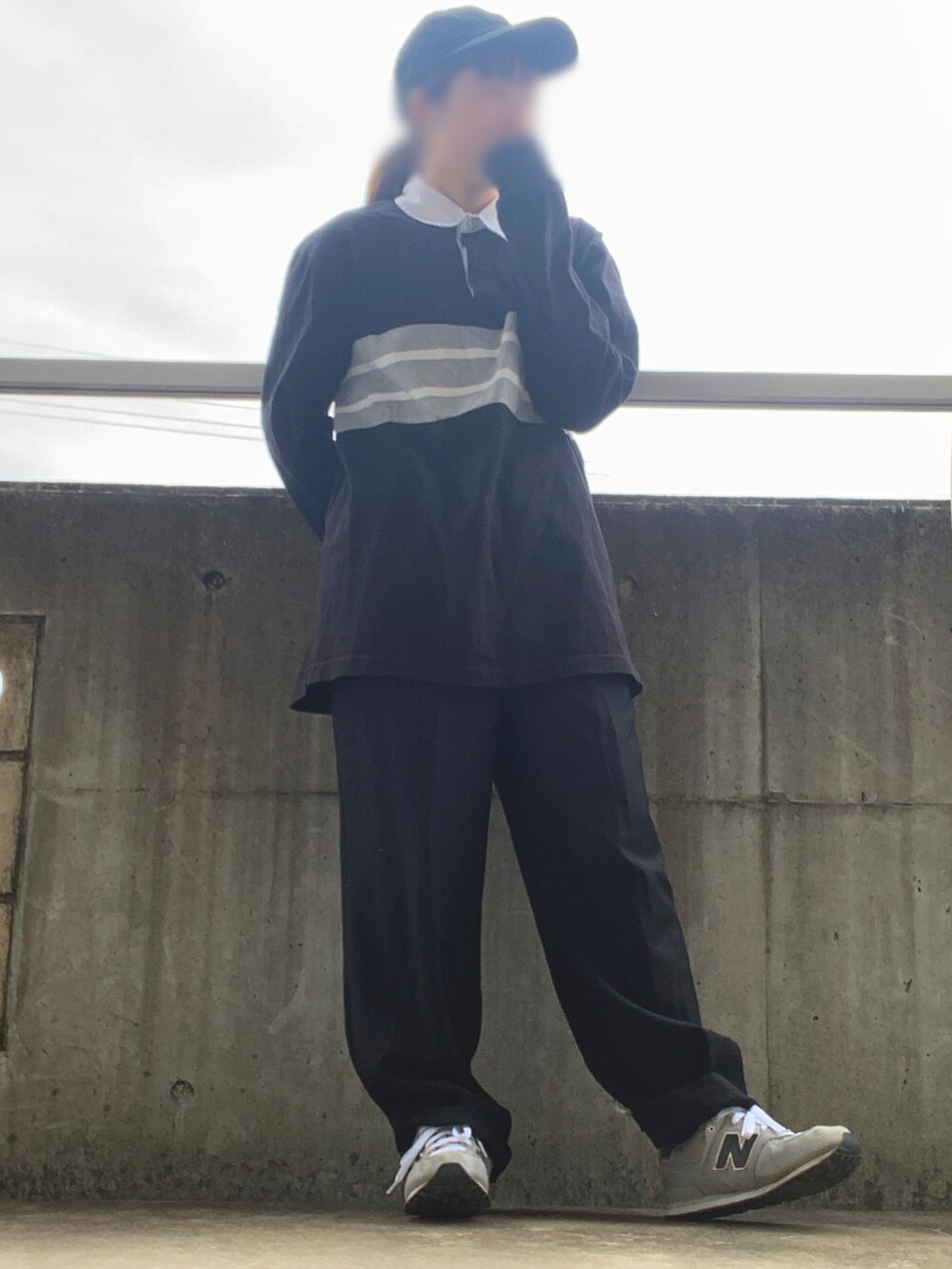 グレー系のスニーカー、ブラック系のスラックス、ブラック系のポロシャツを着用したレディースの冬コーディネートの2枚目の写真