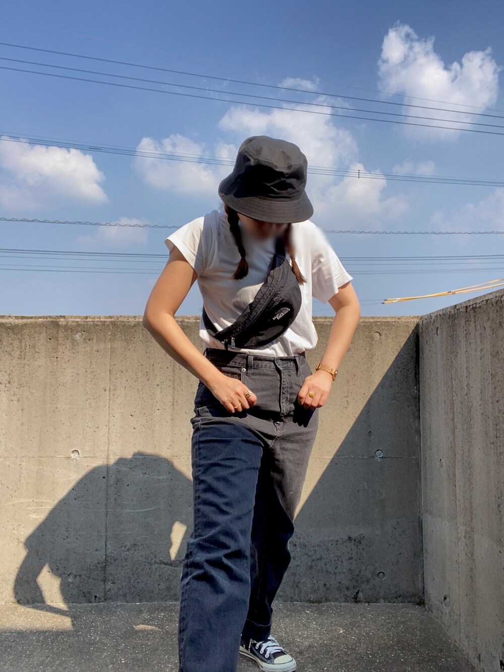 ブラック系のデニムパンツ、ブラック系のボディバッグ/ウエストポーチ、ホワイト系のTシャツ/カットソーを着用したレディースの秋コーディネートの3枚目の写真