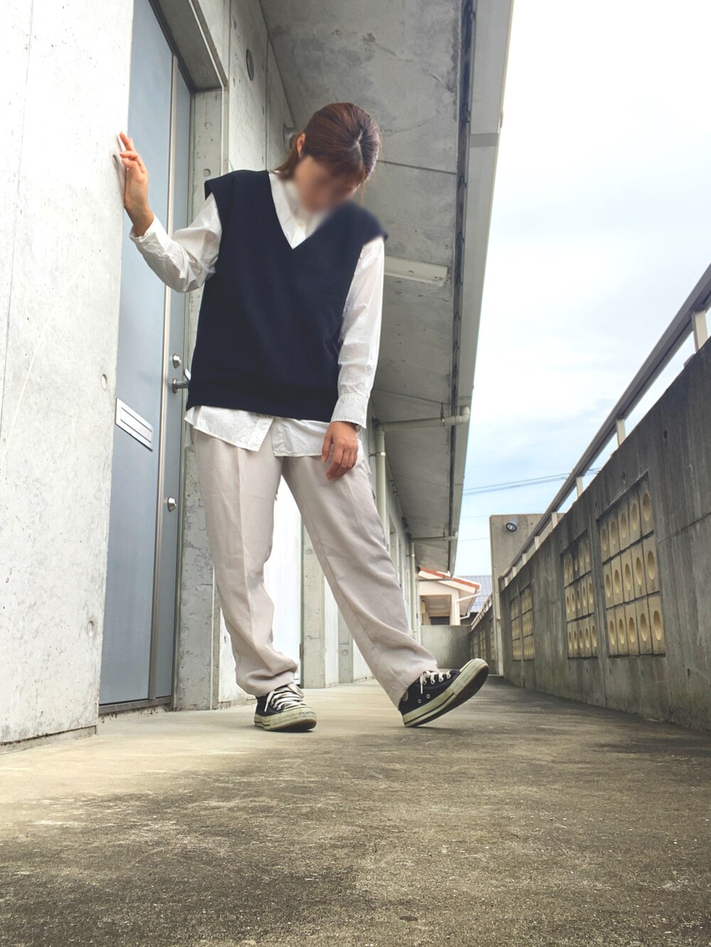 ブラック系のベスト、ホワイト系のパンツ、ブラック系のスニーカーを着用したレディースの秋コーディネートの2枚目の写真