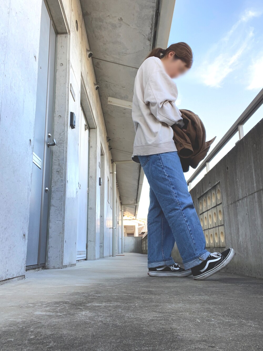 ベージュ系のトップス、ブルー系のデニムパンツ、ブラック系のスニーカーを着用したレディースの秋コーディネートの2枚目の写真