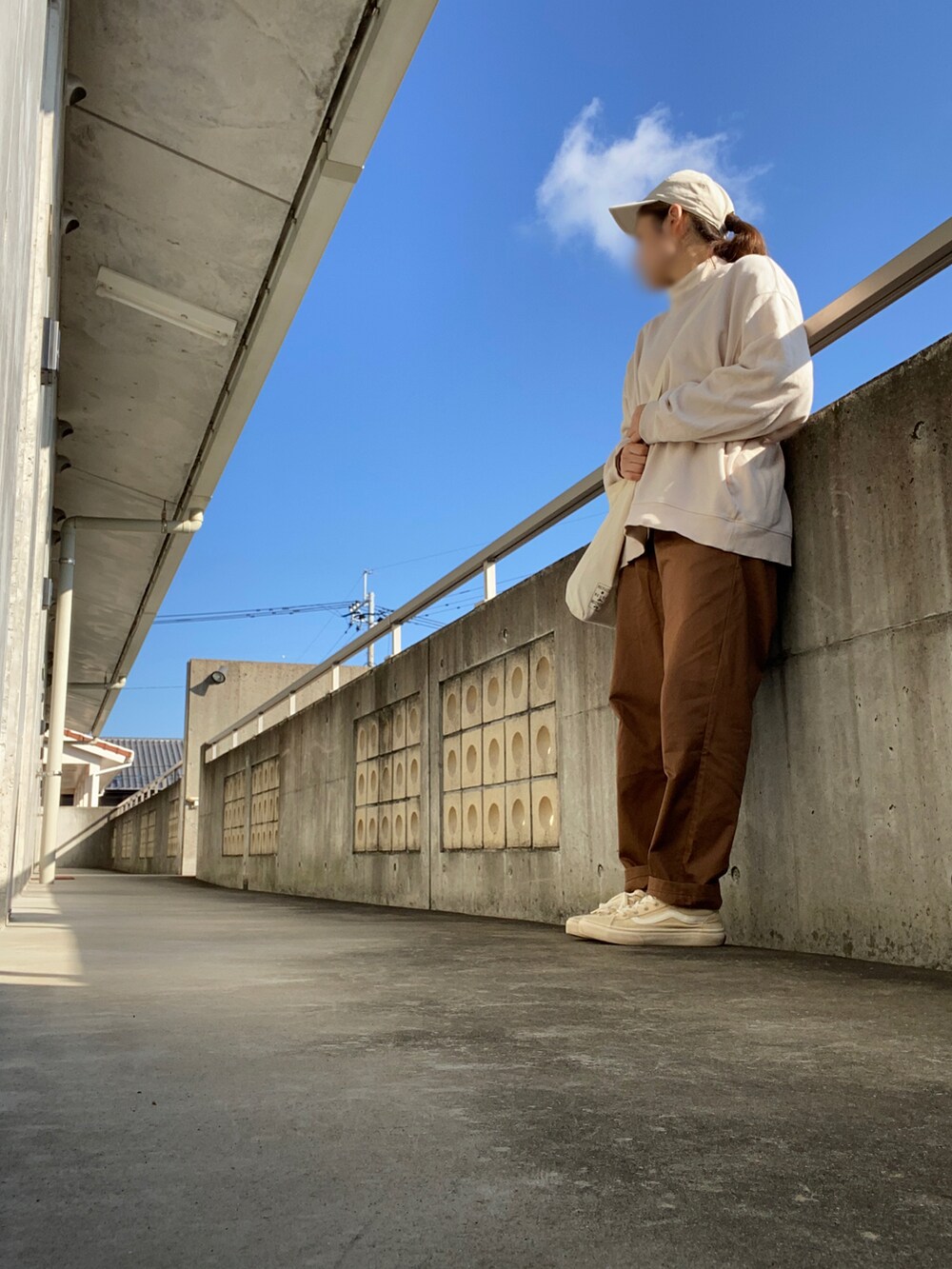 ブラウン系のパンツ、ベージュ系のスニーカー、ベージュ系のバッグを着用したレディースの秋コーディネートの2枚目の写真