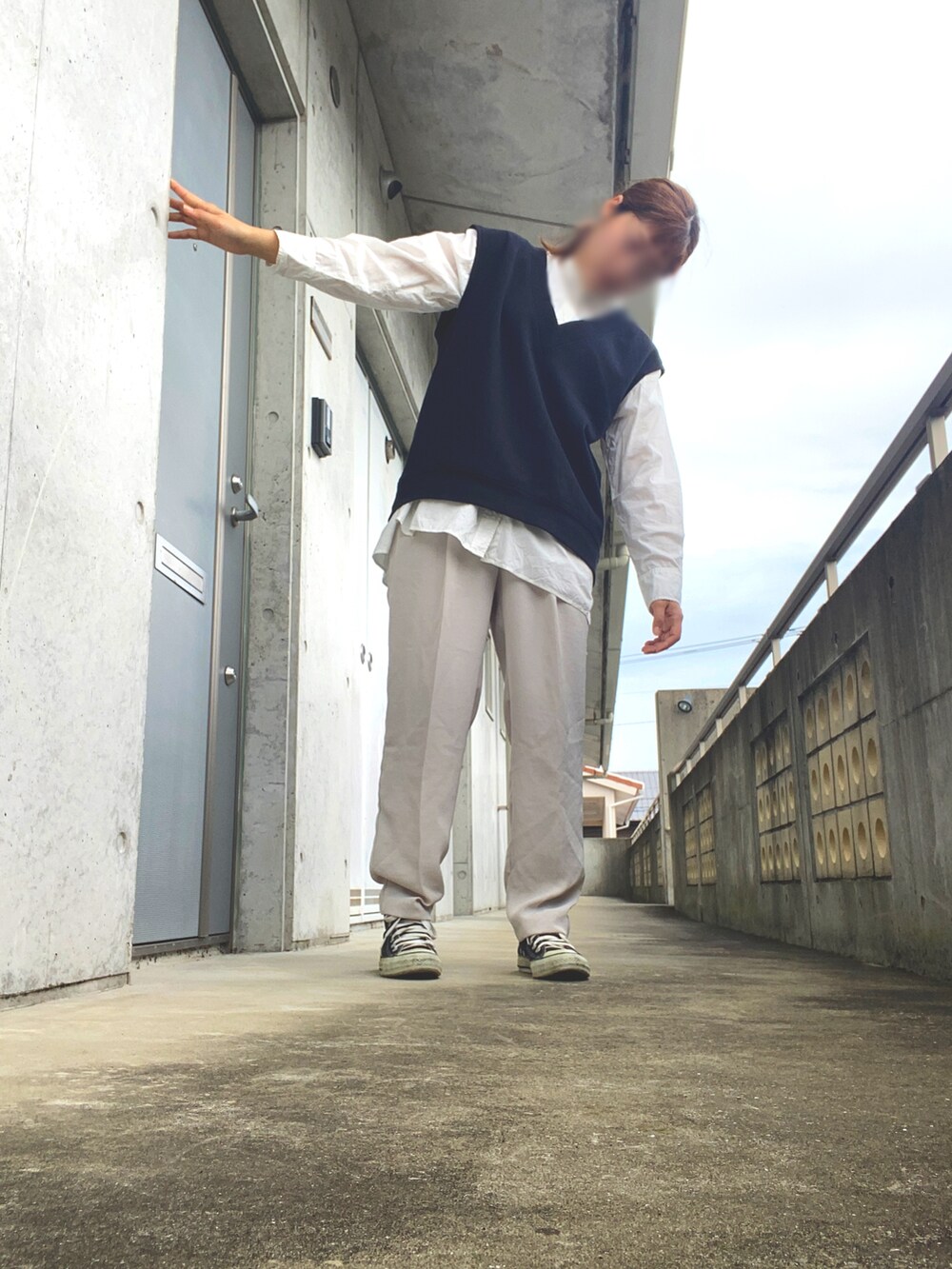 ブラック系のベスト、ホワイト系のパンツ、ブラック系のスニーカーを着用したレディースの秋コーディネートの3枚目の写真