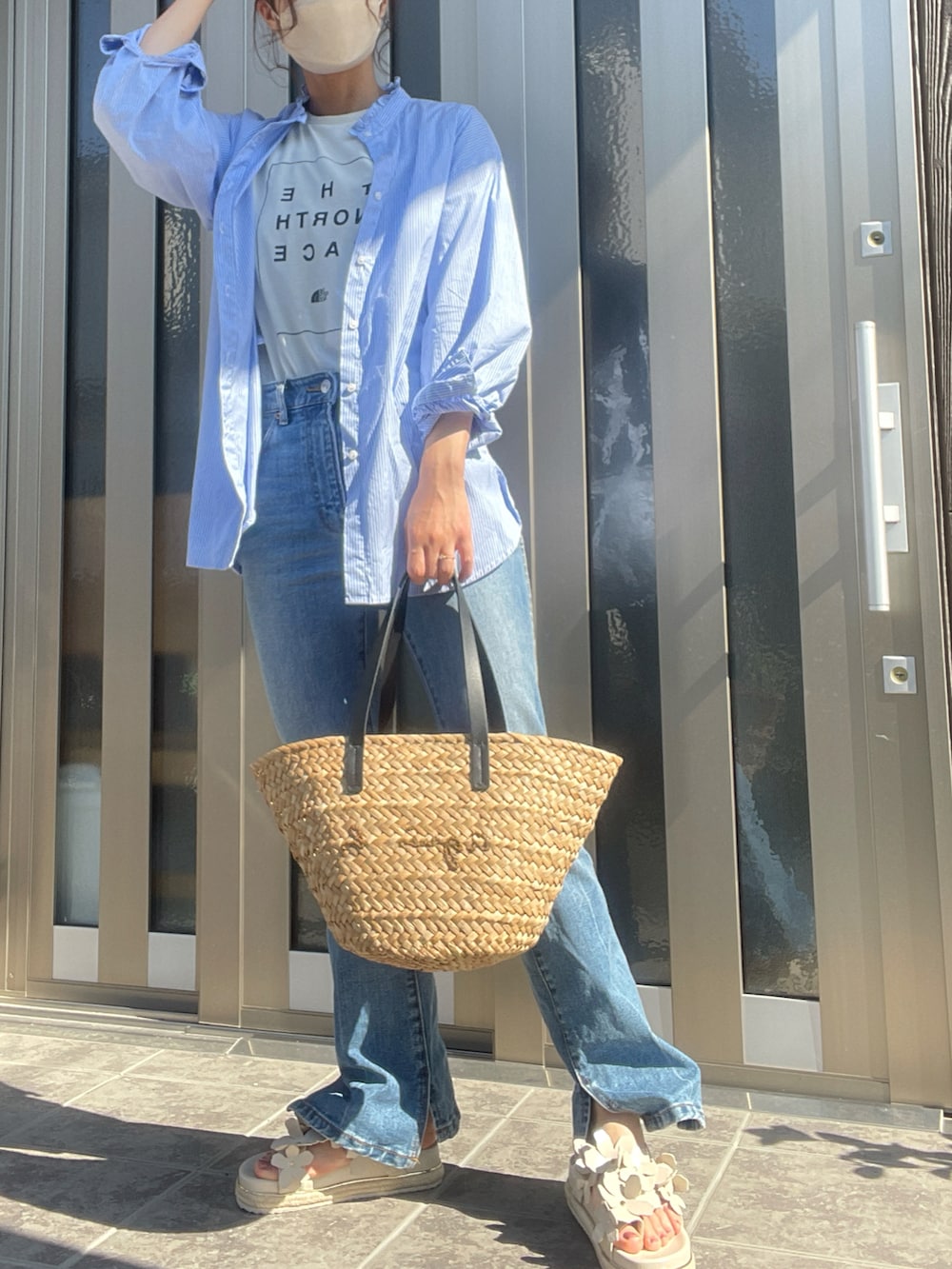 ベージュ系のかごバッグ、ブルー系のデニムパンツ、ホワイト系のサンダルを着用したレディースの夏コーディネートの2枚目の写真
