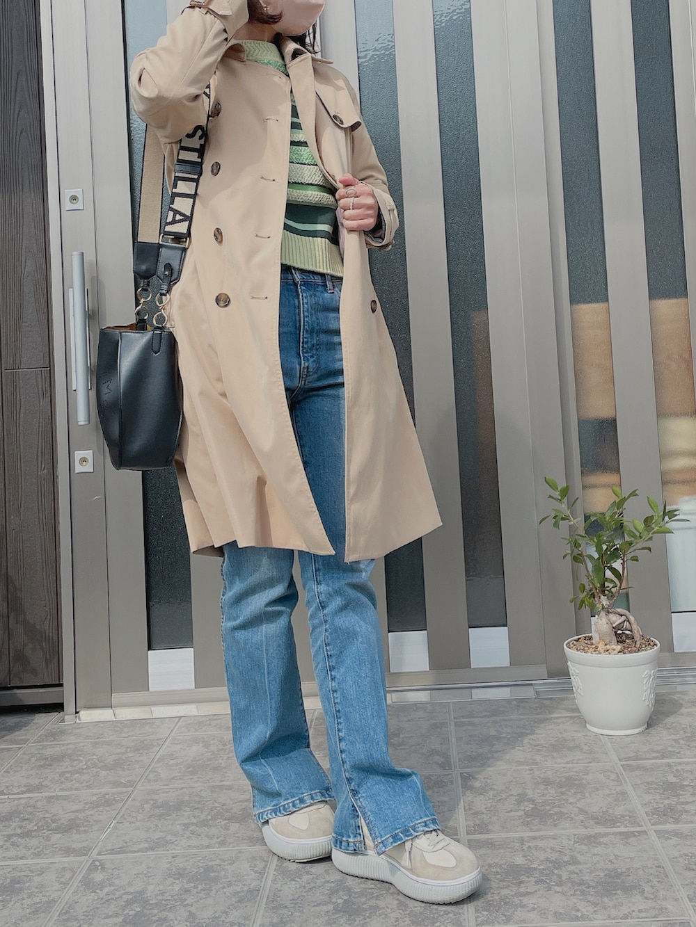 ブルー系のデニムパンツ、ホワイト系のスニーカー、グリーン系のニット/セーターを着用したレディースの春コーディネートの2枚目の写真