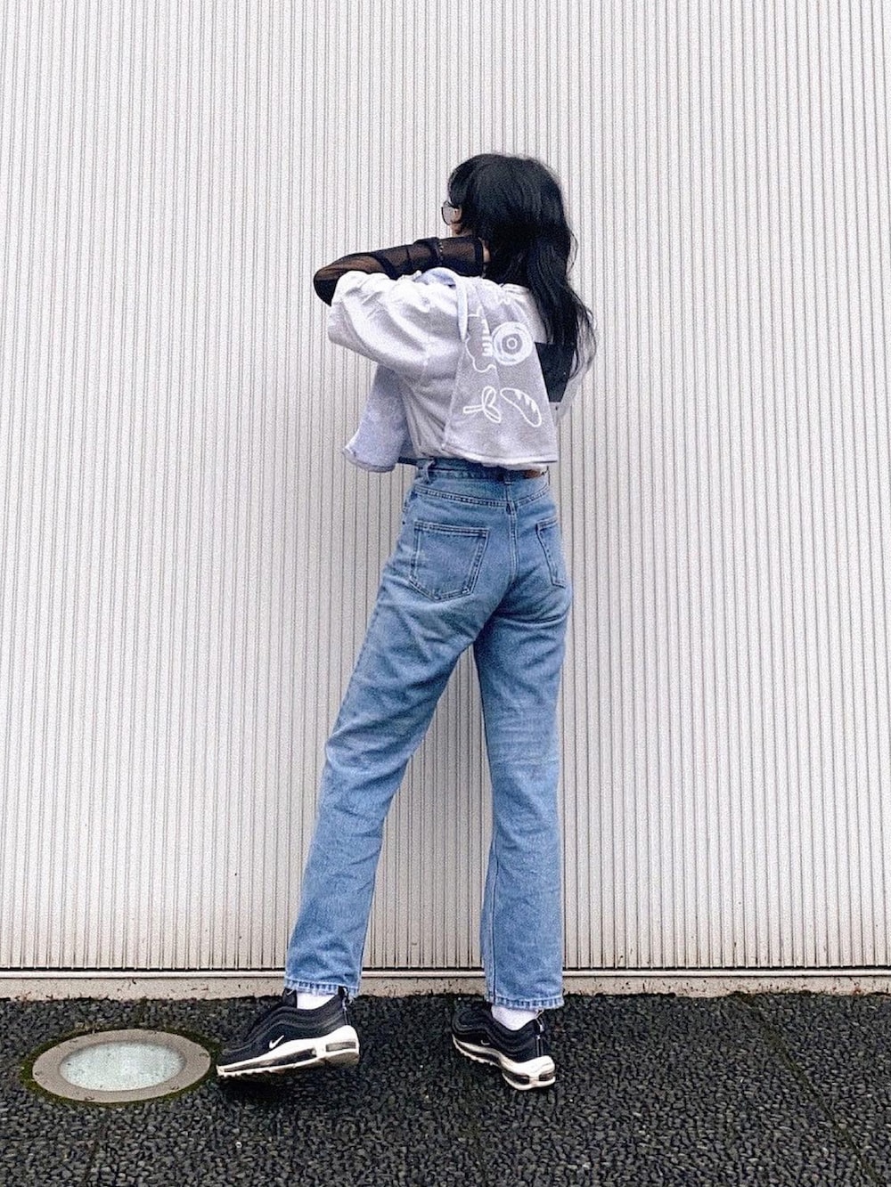 ブルー系のデニムパンツ、ブラック系のスニーカー、ホワイト系のデニムジャケットを着用したレディースの春コーディネートの3枚目の写真