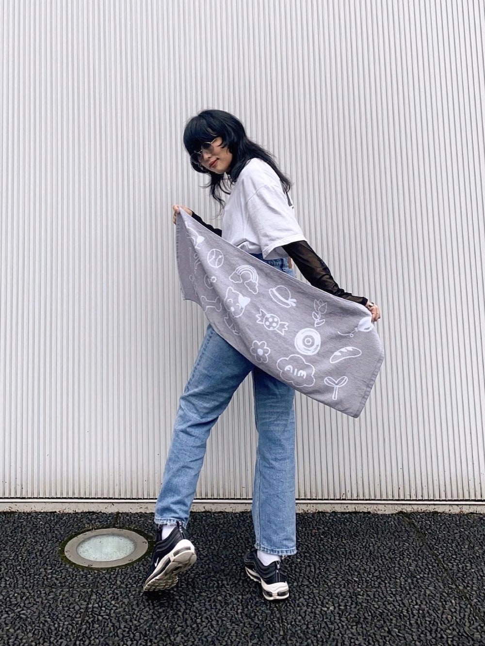 ブルー系のデニムパンツ、ブラック系のスニーカー、ホワイト系のデニムジャケットを着用したレディースの春コーディネートの2枚目の写真