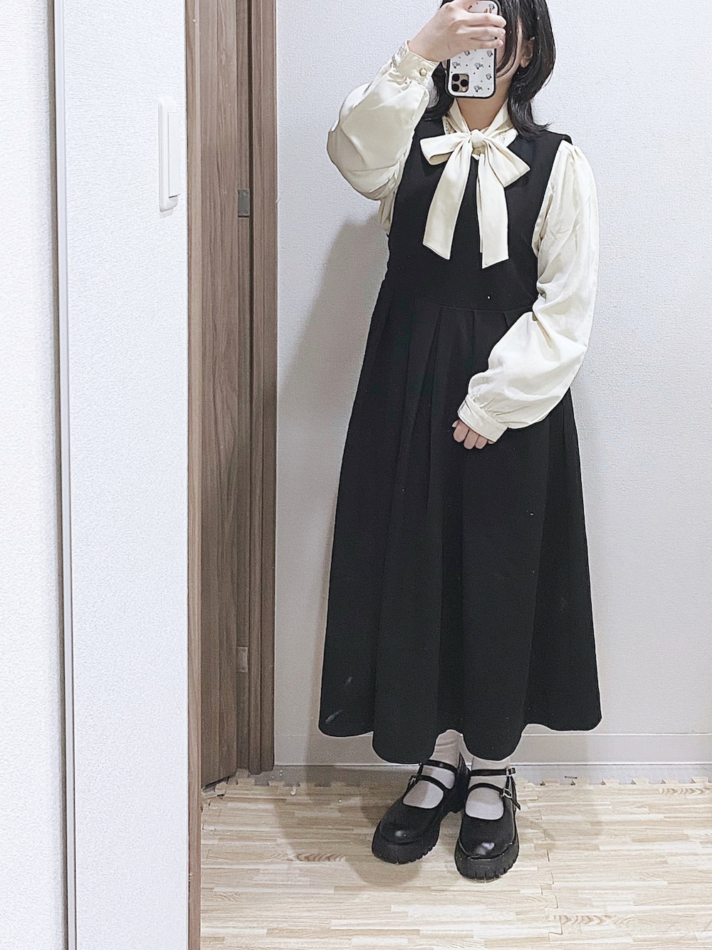 ベージュ系のシャツ/ブラウス、ブラック系のジャンパースカート、ブラック系のドレスシューズを着用したレディースの冬コーディネートの2枚目の写真