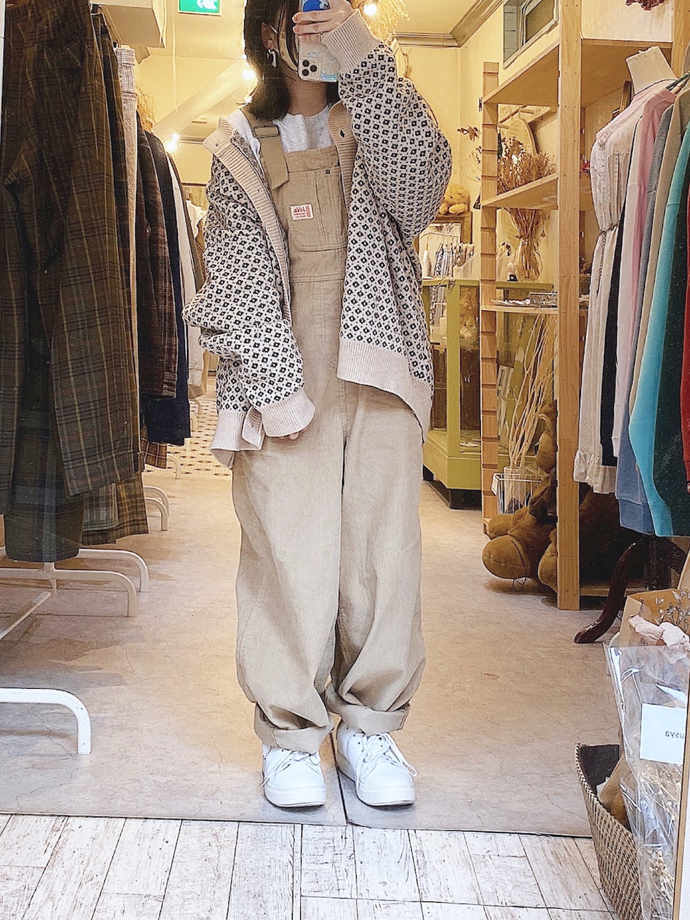 ベージュ系のカーディガン/ボレロ、グレー系のTシャツ/カットソー、ベージュ系のサロペット/オーバーオールを着用したレディースの冬コーディネートの2枚目の写真