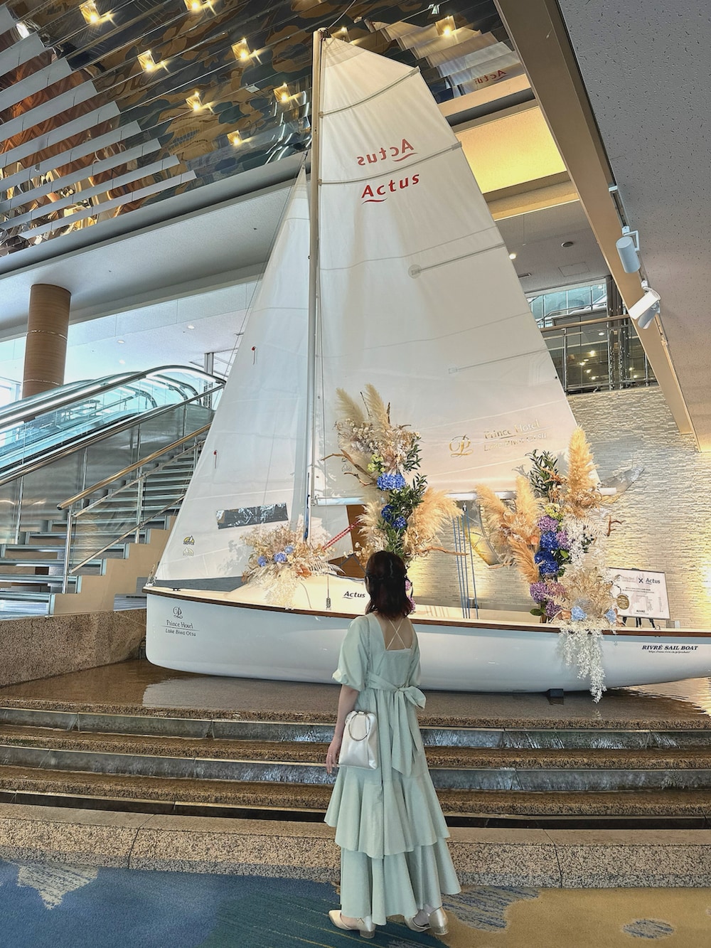 グリーン系のワンピース、ホワイト系のショルダーバッグを着用したレディースの春コーディネートの2枚目の写真