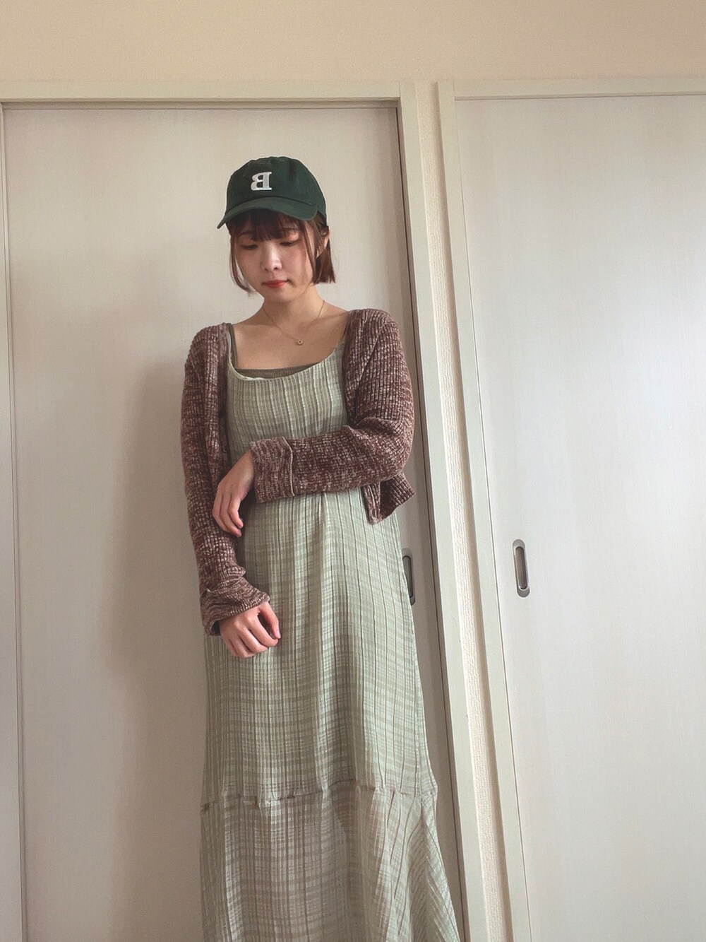 ブラウン系のニット/セーター、グリーン系のワンピース、グリーン系のキャップを着用したレディースの春コーディネートの2枚目の写真