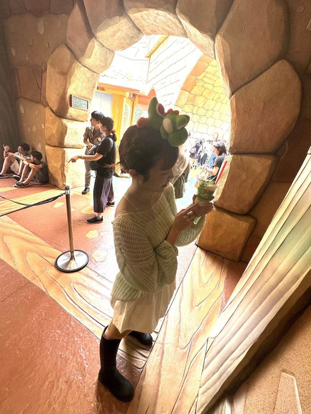 ブラック系のブーツ、グリーン系のニット/セーター、ホワイト系のスカートを着用したレディースの夏コーディネートの2枚目の写真