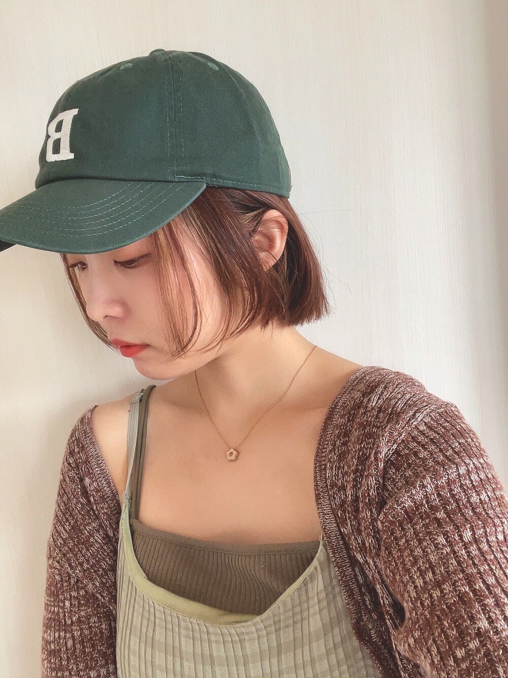 ブラウン系のニット/セーター、グリーン系のワンピース、グリーン系のキャップを着用したレディースの春コーディネートの3枚目の写真