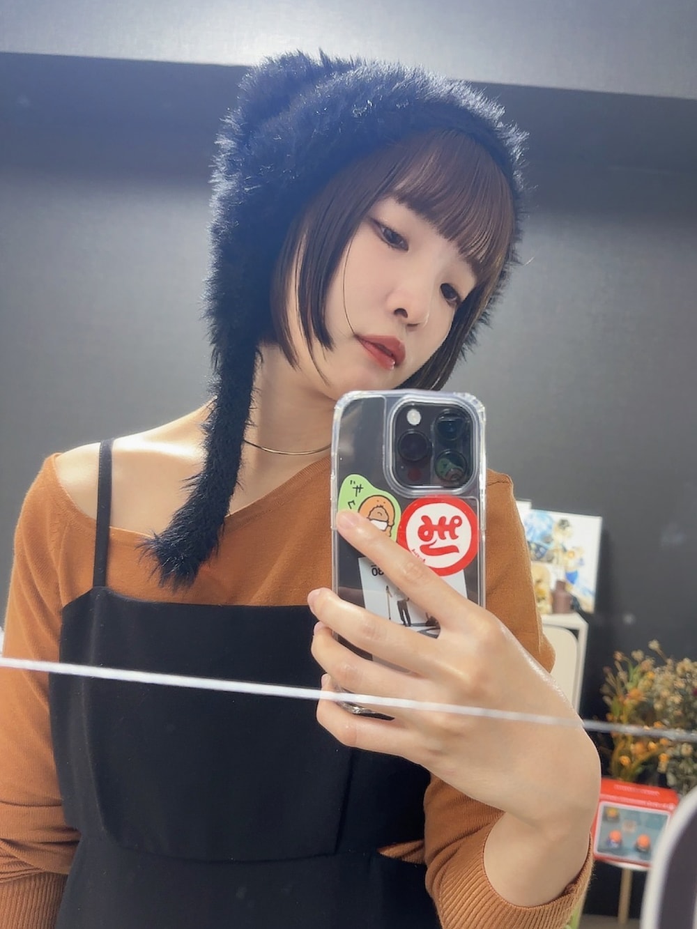 ブラック系のワンピース、オレンジ系のニット/セーター、ブラック系の帽子を着用したレディースの秋コーディネートの3枚目の写真