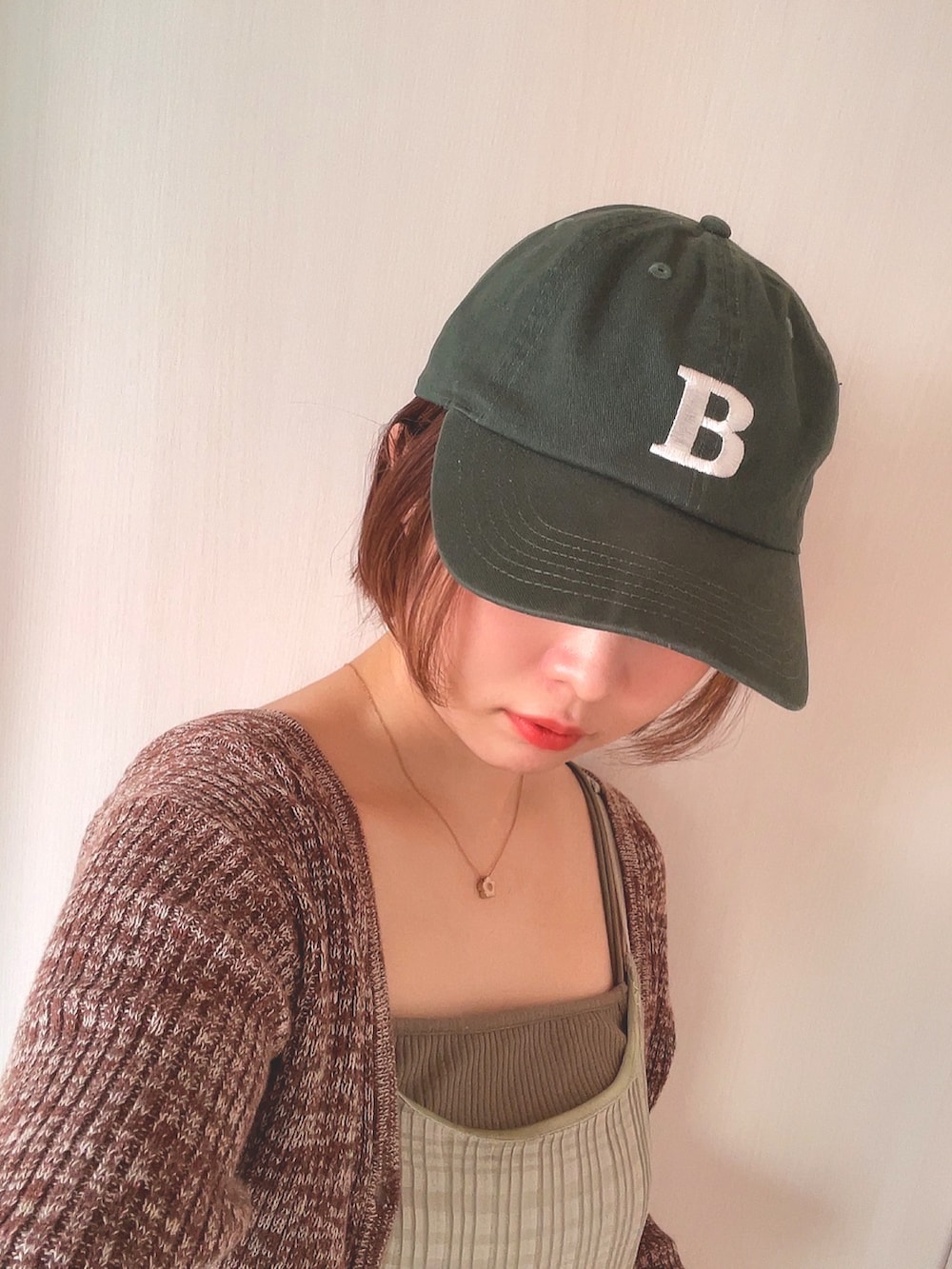 ブラウン系のニット/セーター、グリーン系のワンピース、グリーン系のキャップを着用したレディースの春コーディネートの4枚目の写真