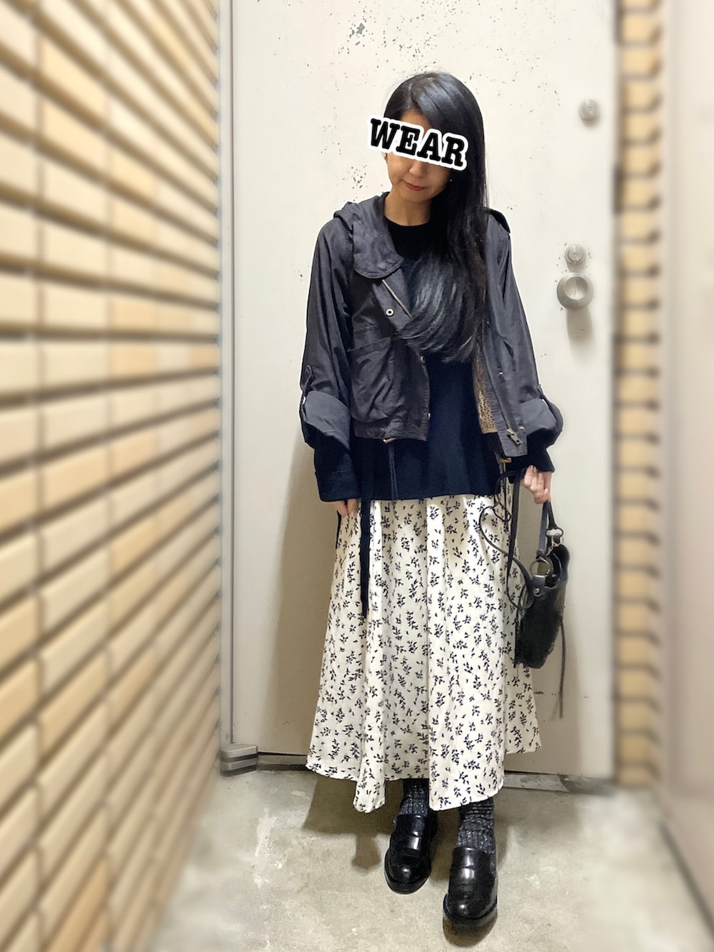 ブラック系のナイロンジャケット、ブラック系のニット/セーター、ホワイト系のスカートを着用したレディースの秋コーディネートの2枚目の写真