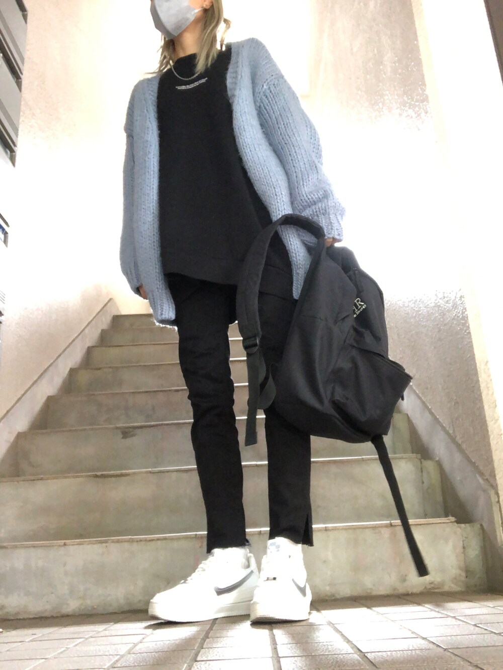 レッド系のショルダーバッグ、ホワイト系のスニーカー、ブラック系のデニムパンツを着用したレディースの秋コーディネートの3枚目の写真