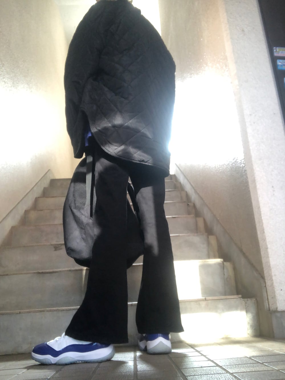 ブラック系のデニムパンツ、ブラック系のブルゾン、レッド系のショルダーバッグを着用したレディースの冬コーディネートの3枚目の写真