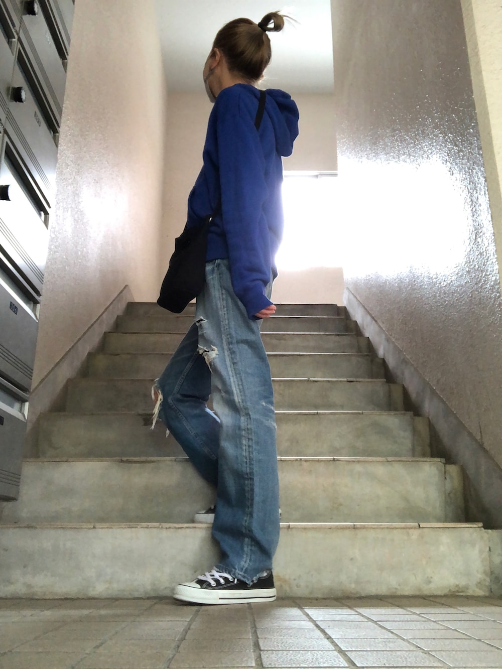 ブルー系のデニムパンツ、ブラック系のショルダーバッグ、ブラック系のスニーカーを着用したレディースの春コーディネートの2枚目の写真