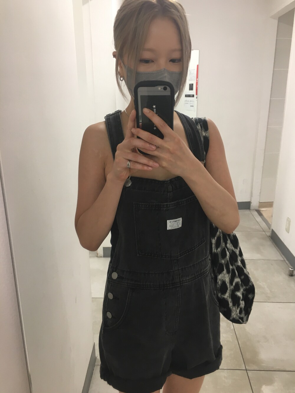 ブラック系のサロペット/オーバーオール、グレー系のトートバッグ、ブラック系のチューブトップを着用したレディースの秋コーディネートの4枚目の写真