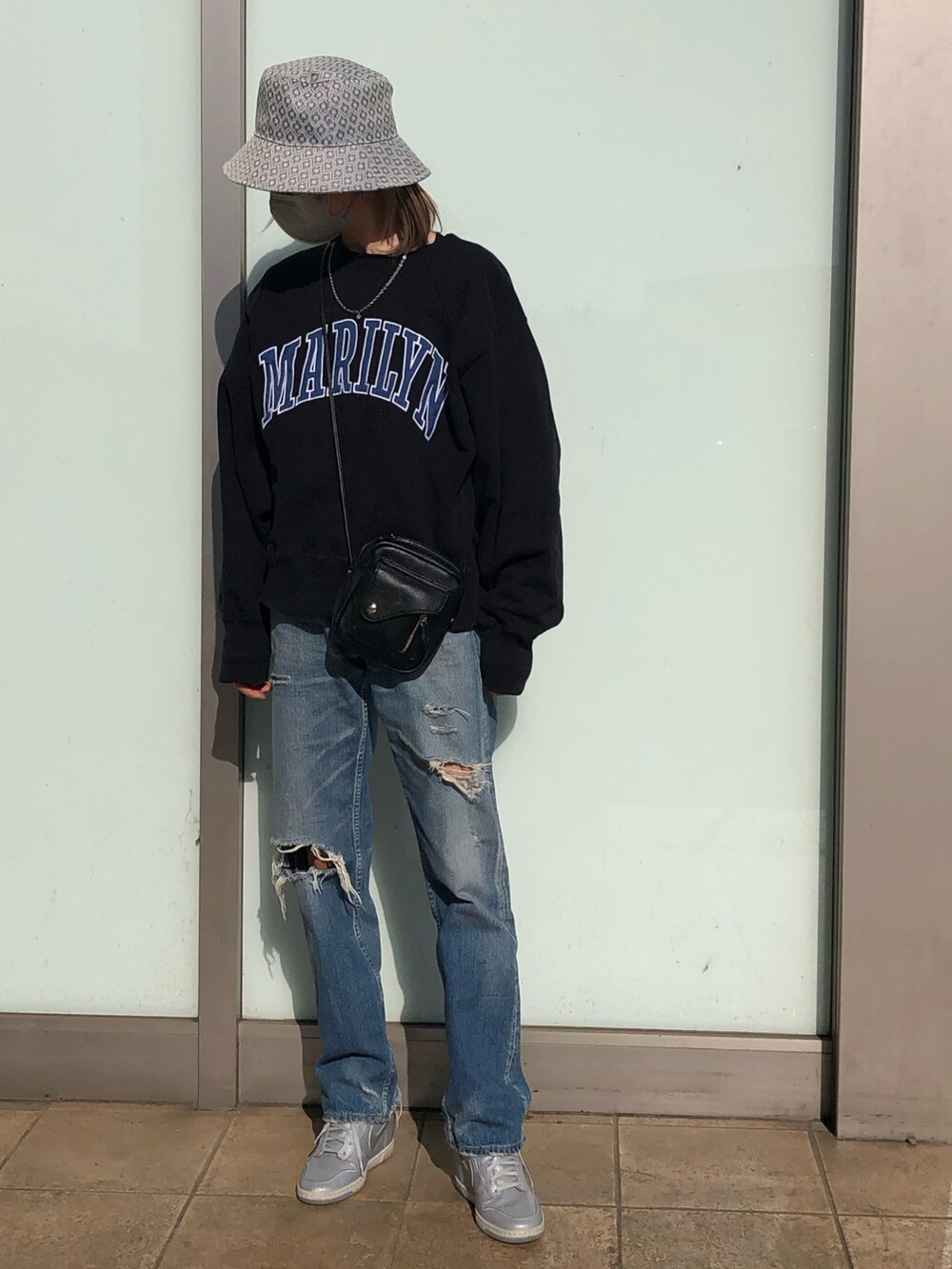 ブルー系のデニムパンツ、ブラック系のショルダーバッグ、ブラック系のスウェットを着用したレディースの春コーディネートの3枚目の写真