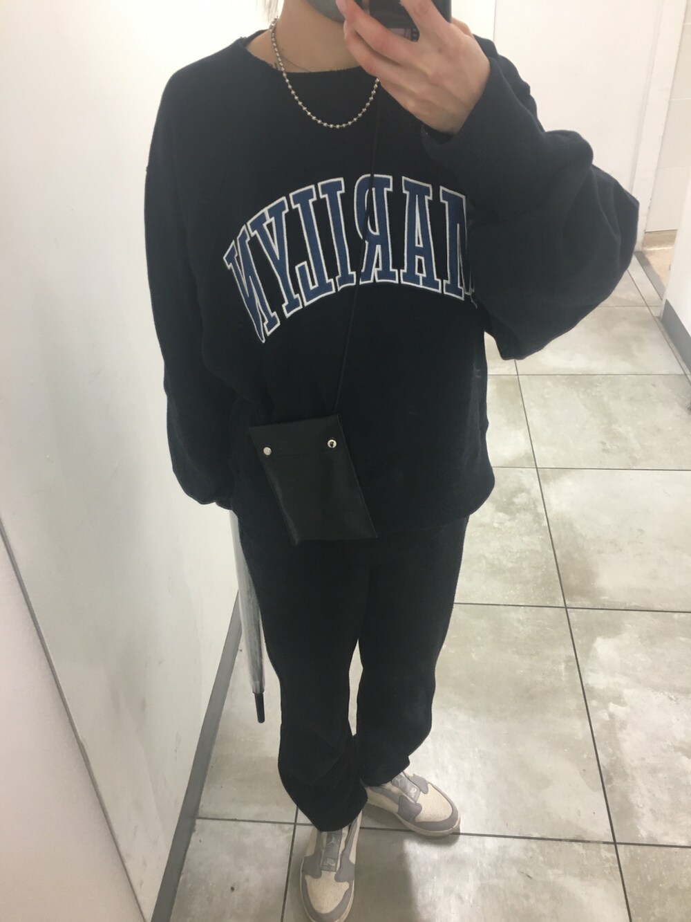 グレー系のスニーカー、ブラック系のスウェット、ブラック系のショルダーバッグを着用したレディースの秋コーディネートの2枚目の写真