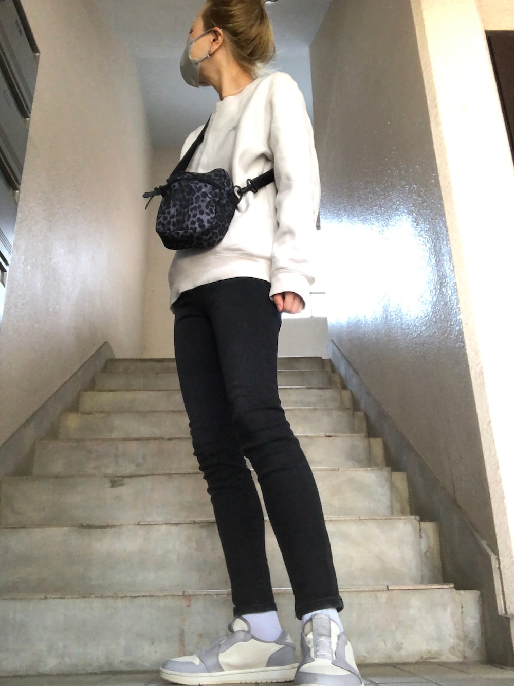 ブルー系のデニムパンツ、グレー系のスニーカー、ブラック系のショルダーバッグを着用したレディースの春コーディネートの3枚目の写真