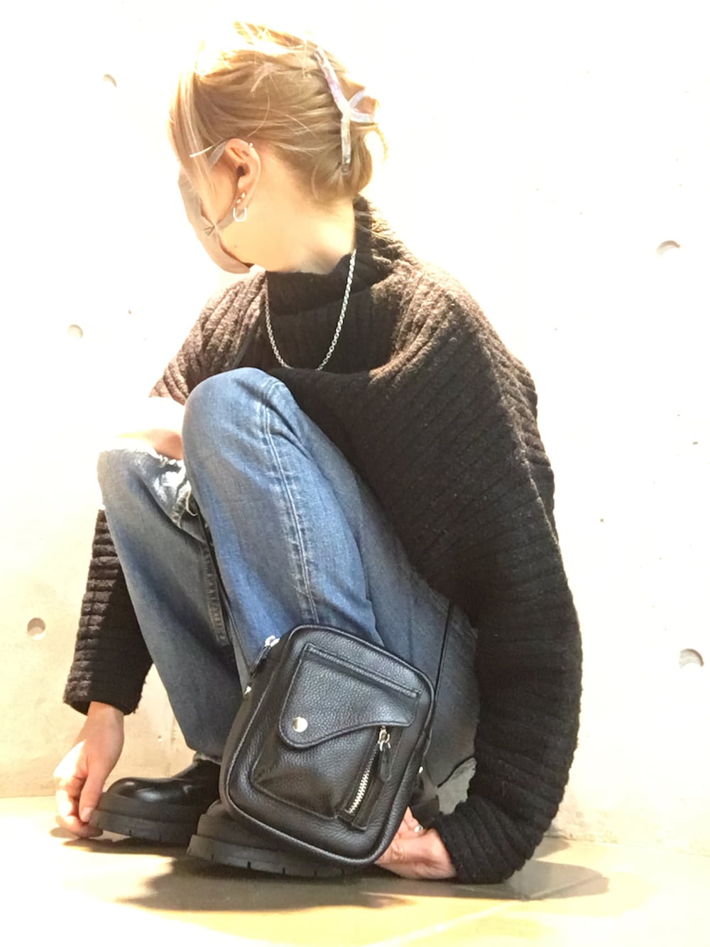 ブラック系のニット/セーター、ブラック系のショルダーバッグ、ホワイト系のブーツを着用したレディースの冬コーディネートの5枚目の写真