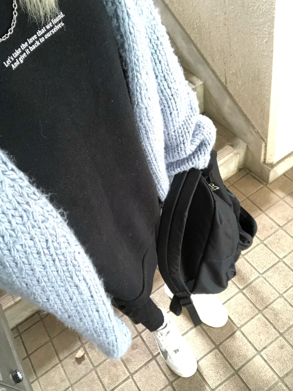 レッド系のショルダーバッグ、ホワイト系のスニーカー、ブラック系のデニムパンツを着用したレディースの秋コーディネートの4枚目の写真