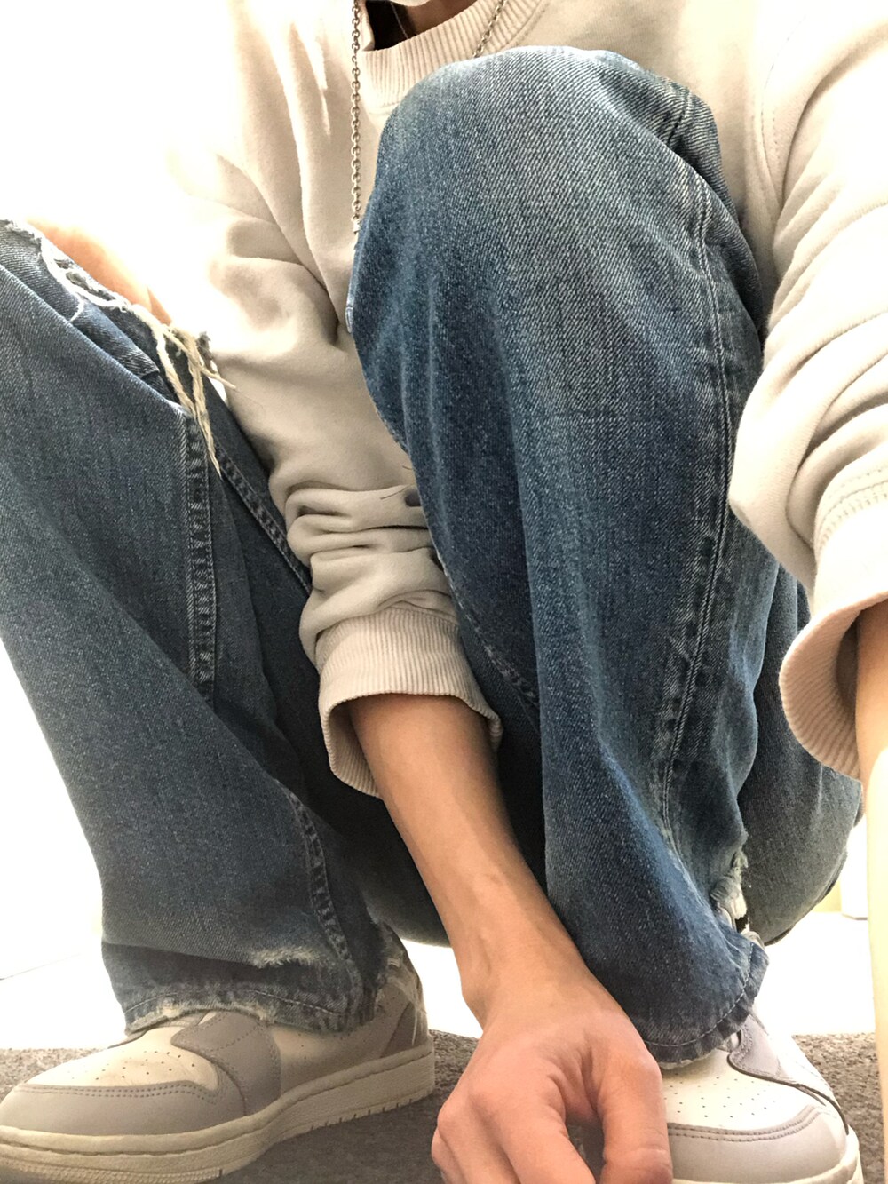 ベージュ系のスウェット、グレー系のスニーカー、ブルー系のデニムパンツを着用したレディースの春コーディネートの3枚目の写真
