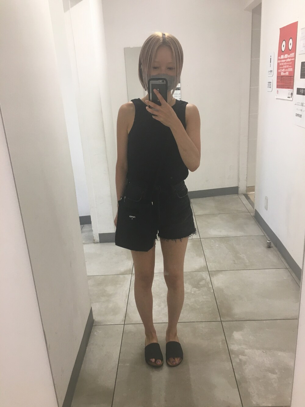 ブラック系のデニムパンツ、ホワイト系のタンクトップ、ゴールド系のサンダルを着用したレディースの秋コーディネートの3枚目の写真