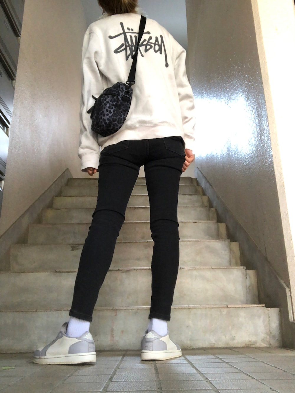 ブルー系のデニムパンツ、グレー系のスニーカー、ブラック系のショルダーバッグを着用したレディースの春コーディネートの2枚目の写真