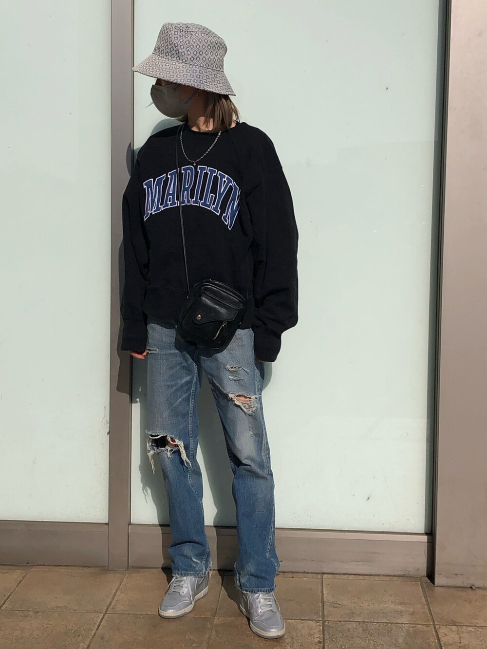 ブルー系のデニムパンツ、ブラック系のショルダーバッグ、ブラック系のスウェットを着用したレディースの春コーディネートの2枚目の写真