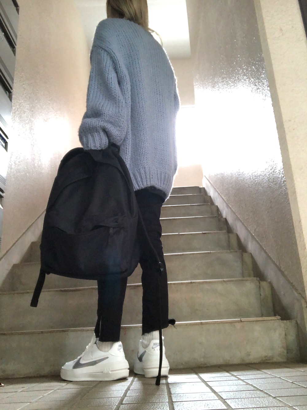 レッド系のショルダーバッグ、ホワイト系のスニーカー、ブラック系のデニムパンツを着用したレディースの秋コーディネートの2枚目の写真