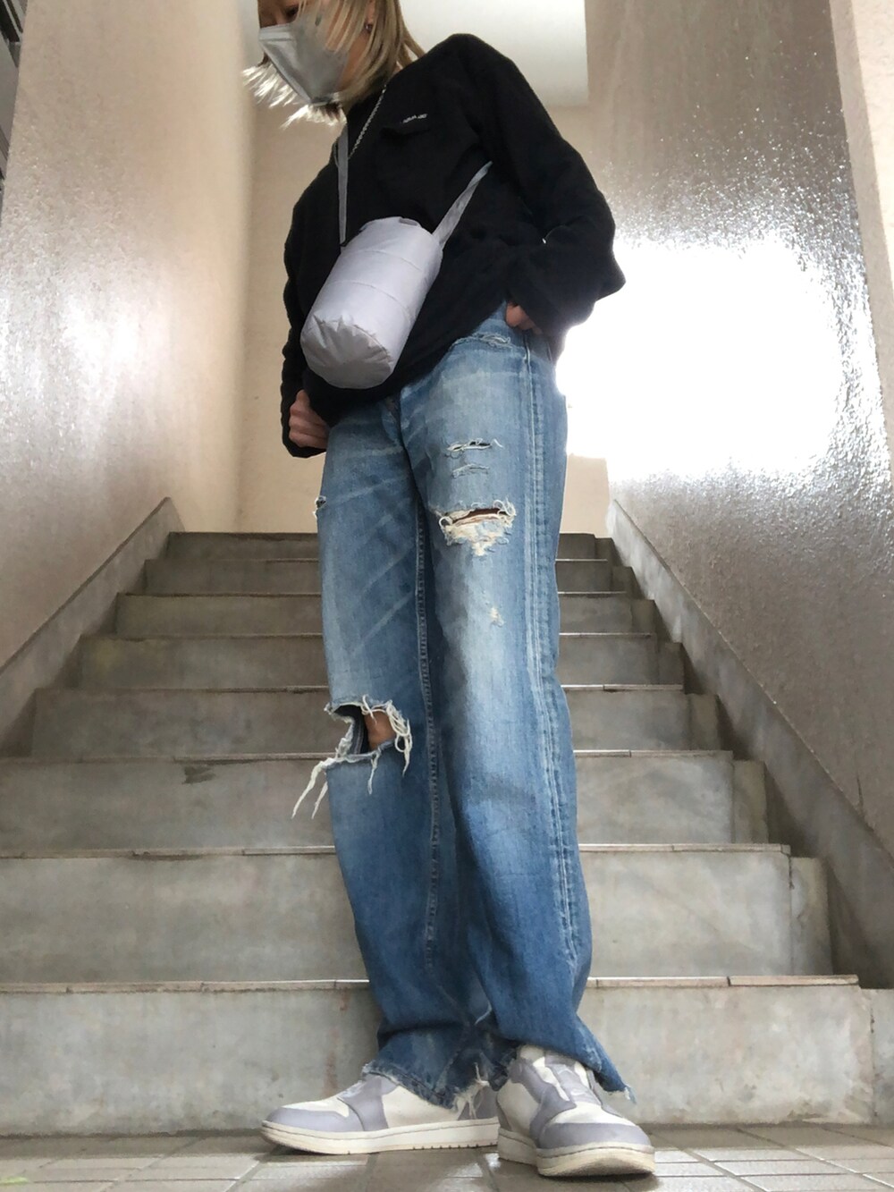 ブルー系のデニムパンツ、ブラック系のTシャツ/カットソー、グレー系のスニーカーを着用したレディースの春コーディネートの2枚目の写真