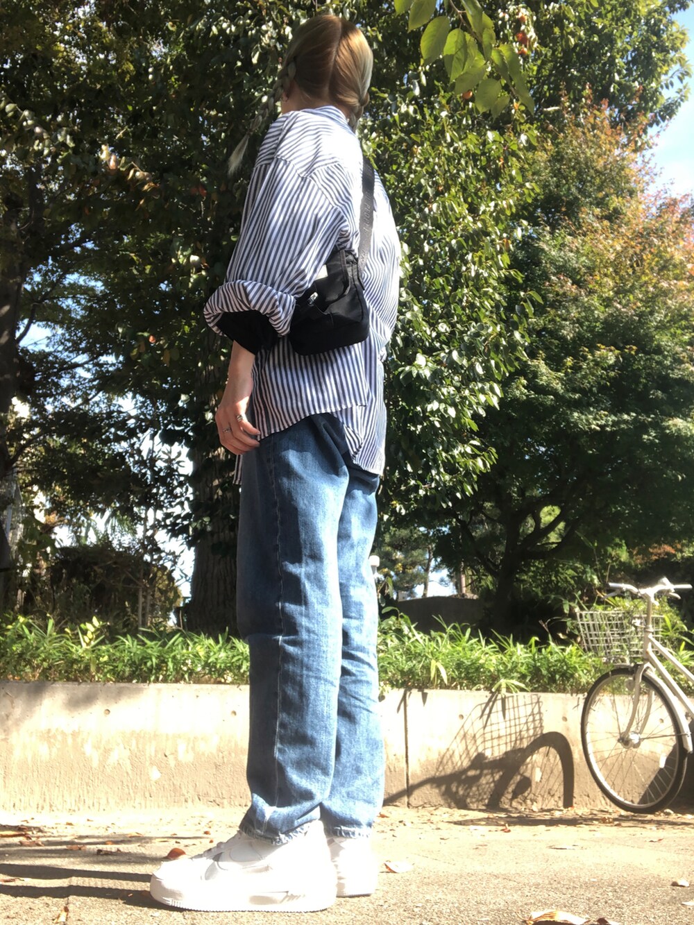 ブルー系のデニムパンツ、ホワイト系のスニーカー、ブルー系のシャツ/ブラウスを着用したレディースの秋コーディネートの2枚目の写真