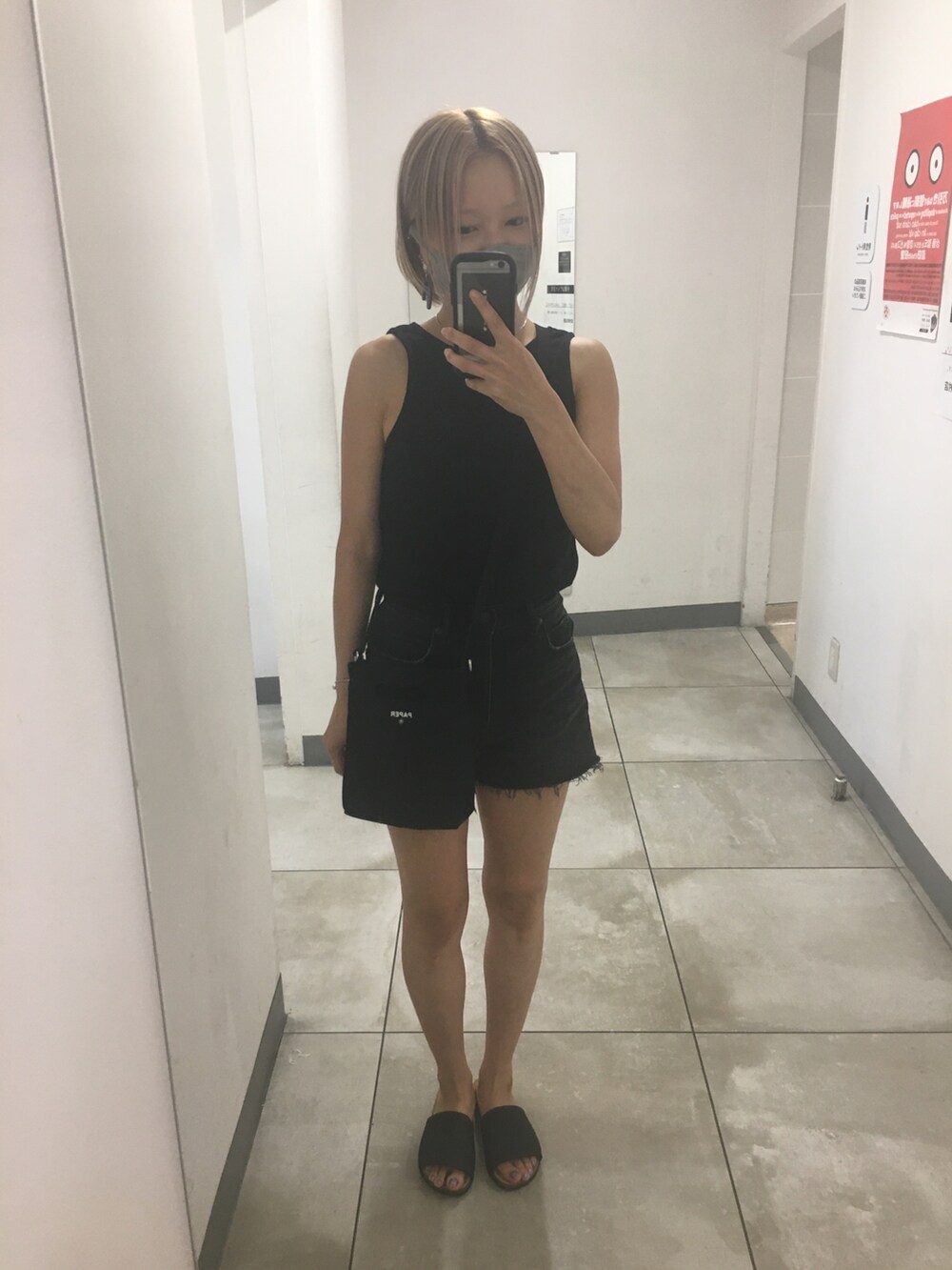 ブラック系のデニムパンツ、ホワイト系のタンクトップ、ゴールド系のサンダルを着用したレディースの秋コーディネートの4枚目の写真