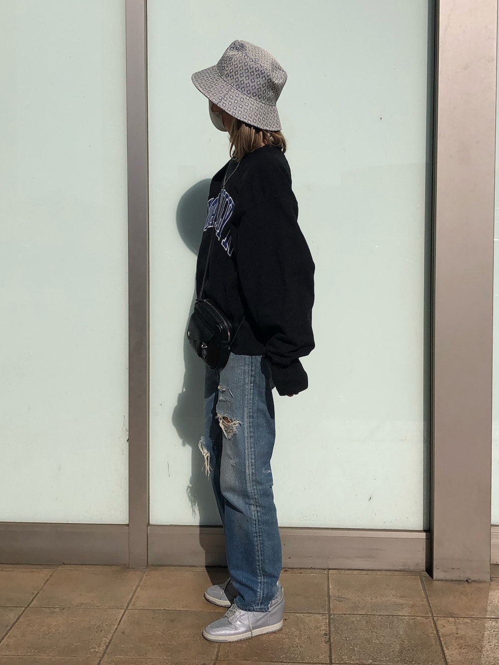 ブルー系のデニムパンツ、ブラック系のショルダーバッグ、ブラック系のスウェットを着用したレディースの春コーディネートの4枚目の写真