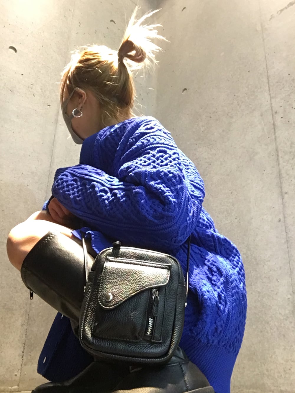 ブラック系のブーツ、ブルー系のニット/セーター、ブラック系のショルダーバッグを着用したレディースの冬コーディネートの4枚目の写真