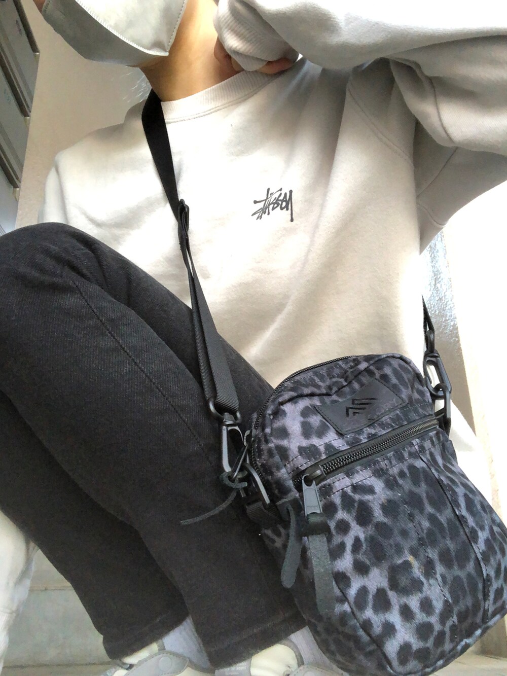 ブルー系のデニムパンツ、グレー系のスニーカー、ブラック系のショルダーバッグを着用したレディースの春コーディネートの4枚目の写真