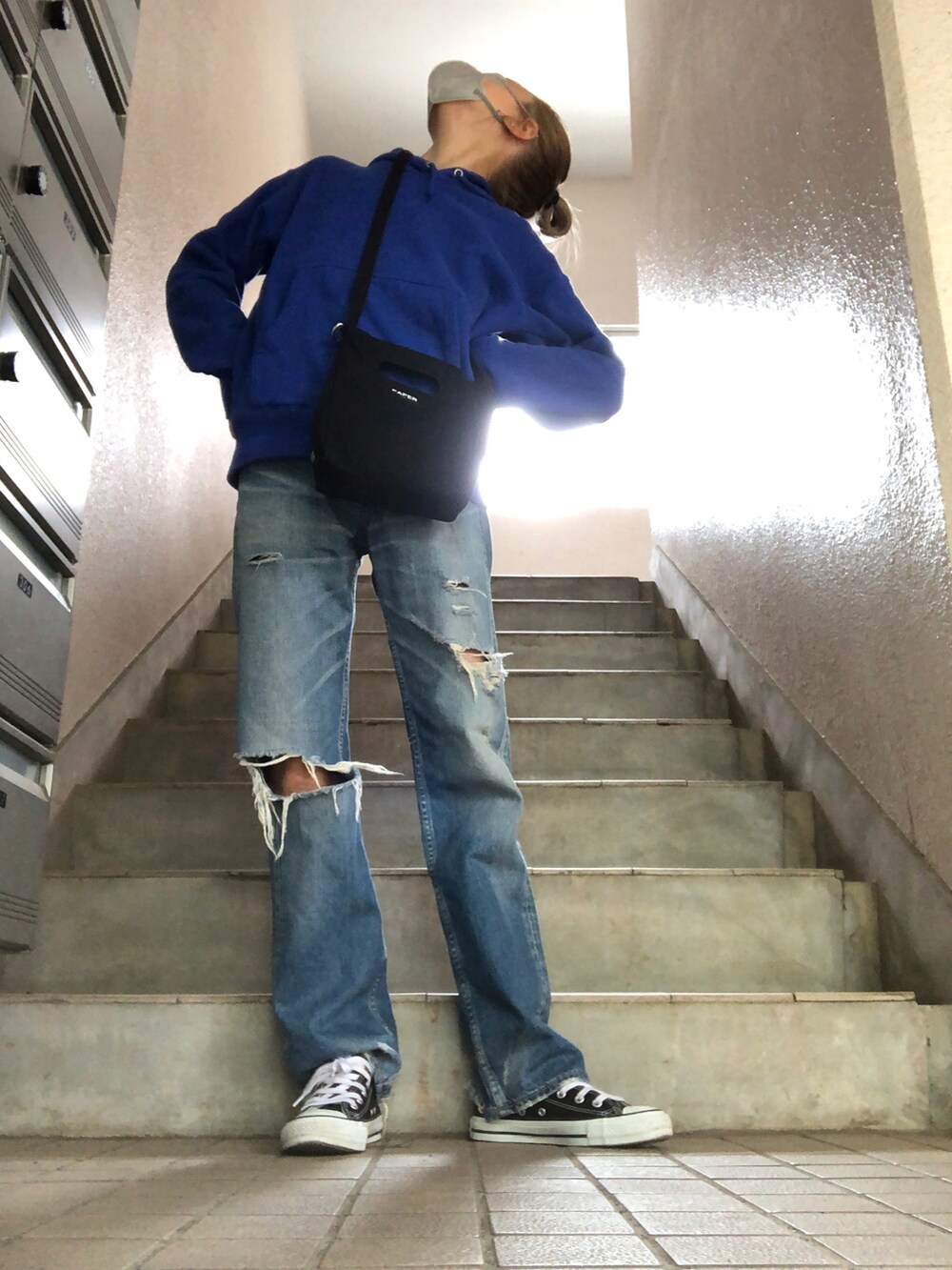 ブルー系のデニムパンツ、ブラック系のショルダーバッグ、ブラック系のスニーカーを着用したレディースの春コーディネートの3枚目の写真