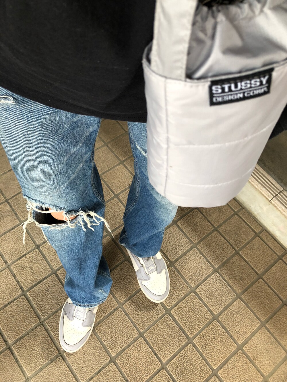 ブルー系のデニムパンツ、ブラック系のTシャツ/カットソー、グレー系のスニーカーを着用したレディースの春コーディネートの5枚目の写真